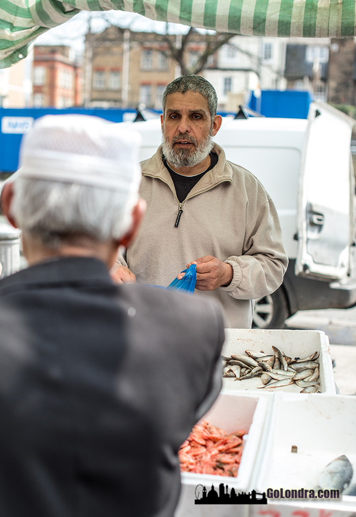 Tower Hamlets ilçesinde yer alan Whitechapel Market'de bulunan bir balıkçı ve müşterisi.